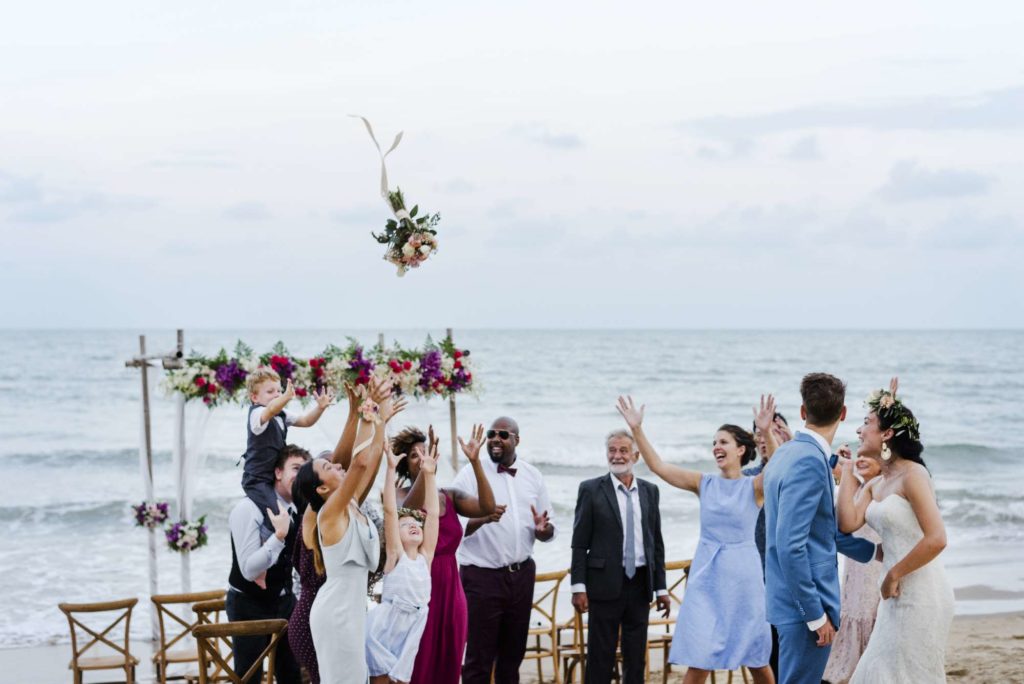 la mariée envoie son bouquet de fleur aux invités sur une plage. 