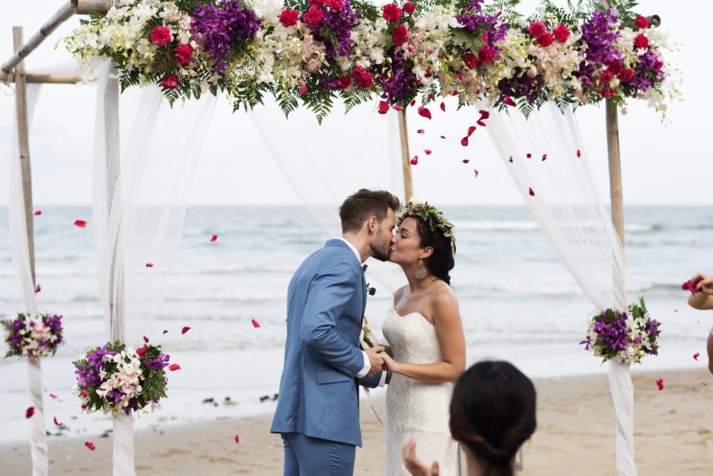 Cérémonie sur la plage, les mariés s'embrassent.